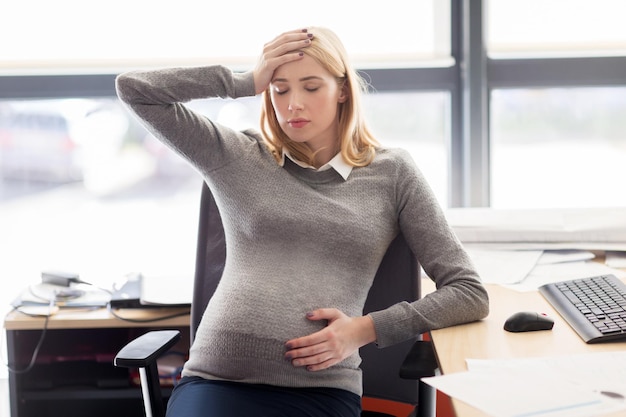 Foto zwangerschap, zaken, stress, gestosis en werkconcept - zwangere zakenvrouw die zich ziek voelt op kantoorwerk