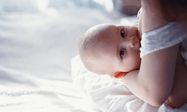 Zwangerschapsconcept Een jonge moeder voedt haar kleine baby Eerste lokaas en borstvoeding Groot gezin in witte kleren