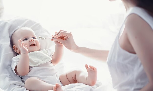 Zwangerschapsconcept Een jonge moeder voedt haar kleine baby Eerste lokken en borstvoeding Familie in witte kleren