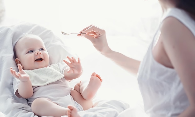 Zwangerschapsconcept Een jonge moeder voedt haar kleine baby Eerste lokken en borstvoeding Groot gezin in witte kleren