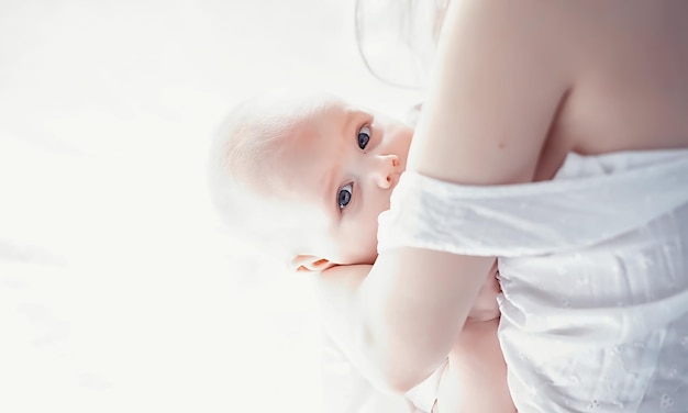 Zwangerschapsconcept Een jonge moeder voedt haar kleine baby Eerste lokken en borstvoeding Groot gezin in witte kleren