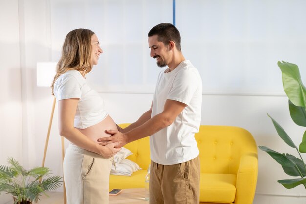 Foto zwangerschapspaar glimlacht gelukkig en raakt de buik aan.