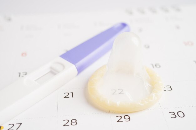 Zwangerschapstest en condoom voor vrouwen op de dag van de kalenderovulatie