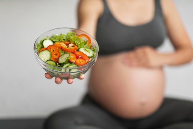Zwangerschapsvoeding Onherkenbare zwangere vrouw met kom met verse groentesalade