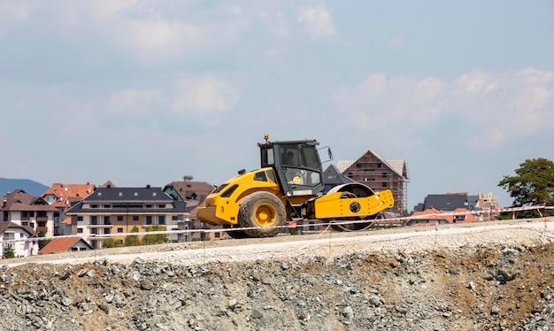 Zware betonnen bestratingsmachine op de weg tegen de achtergrond van mooie huizen