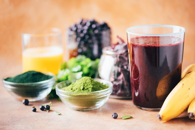 Zware metalen detox smoothie bosbessen blauwe bosbes gerst grassap extract spirulina poeder sinaasappelsap dulse en koriander op marmeren achtergrond Gezond eten alkalisch dieet veganistisch concept