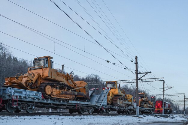 Zware mijnbouwbulldozers op open perrons voor vrachtspoorwegen.