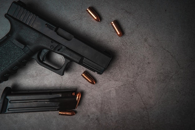 Zwart 9 mm pistool op een oude betonnen vloer met 9 mm munitie ernaast bovenaanzicht