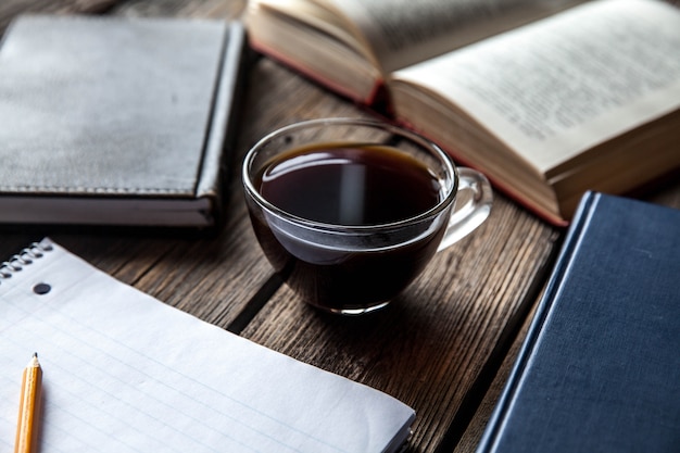 Zwart boek en een kopje koffie op een houten tafel