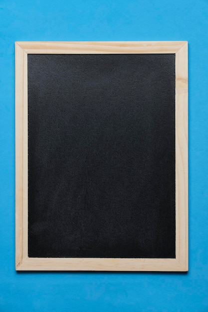 Zwart bord voor notities op houten frame blauwe achtergrond