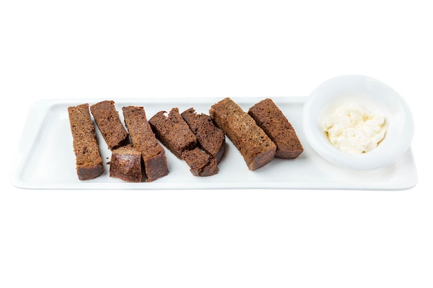 Zwart brood croutons met saus in een witte snack plaat Smakelijke populaire snack voor bier close-up bovenaanzicht geïsoleerd op een witte achtergrond