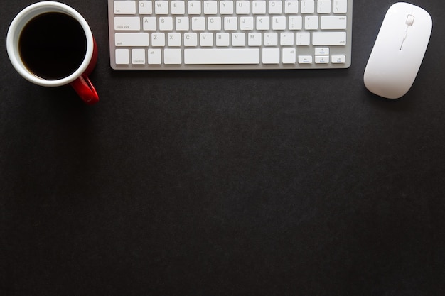 Zwart bureau met laptop, smartphone en andere werkbenodigdheden met kopje koffie. Bovenaanzicht met kopieerruimte voor het invoeren van de tekst. Designer werkruimte op bureau tafel essentiële elementen op plat leggen.