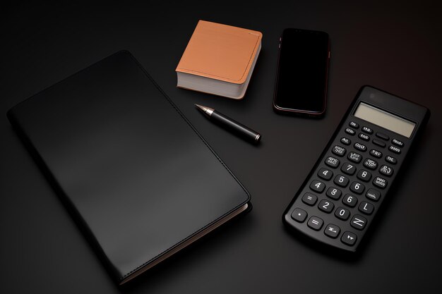Zwart bureaublad met rekenmachine en telefoon naast zwart notebook.