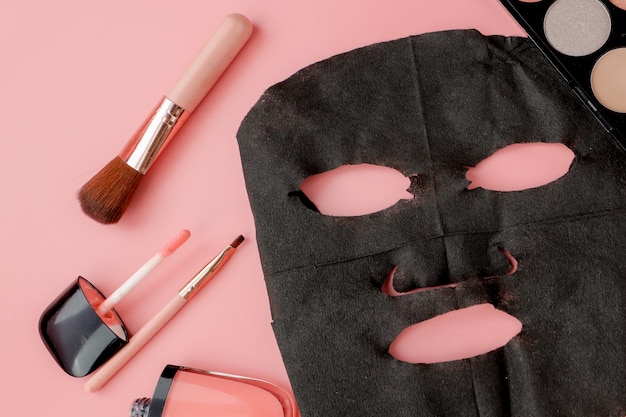 Zwart cosmetisch masker en make-up ingesteld op roze