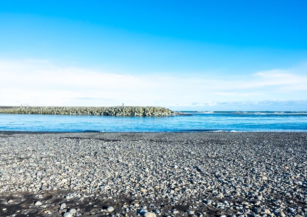 Zwart diamantzandstrand met golf- en sneeuwbergen in het winterseizoen in IJsland