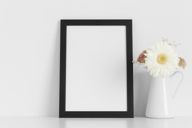 Zwart frame mockup met een boeket bloemen op de witte tafel