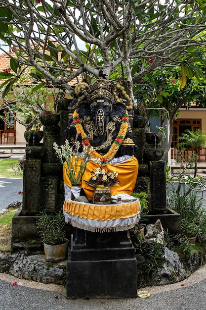 Zwart Ganesha-beeld met een krans van bloemen.