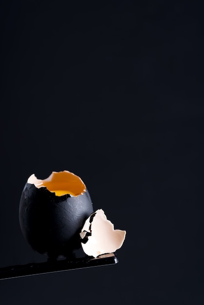 Zwart geschilderd gebroken rauw ei met verse gele dooier