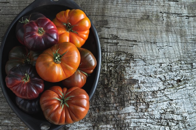 Zwart keramisch dienblad met raf-tomaten en blauwe zee op oude houten achtergrond Kopieer ruimte Bovenaanzicht