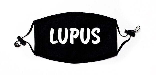 Zwart medisch gezichtsmasker op een lichte ondergrond met de inscriptie LUPUS. Ziektepreventie