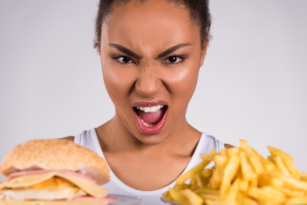 Foto zwart meisje dat bij hamburger en gebraden gerechten gilt.