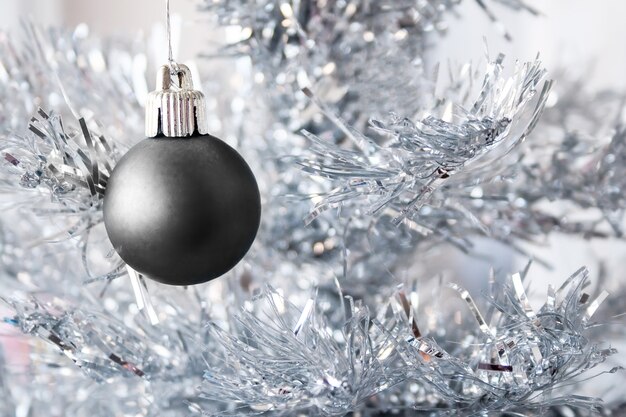 Zwart metallic bal op een zilveren kunstkerstboom