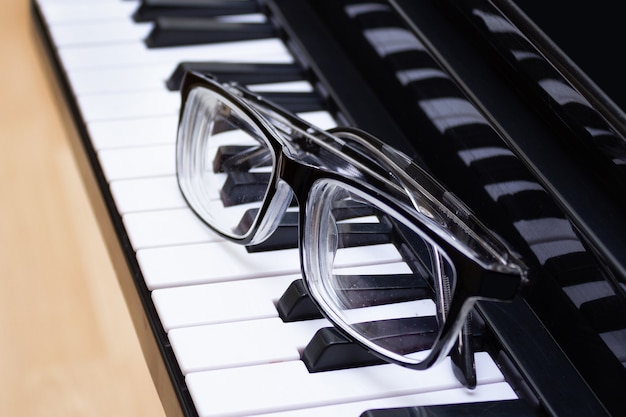 Zwart omrande bril op de toetsen van een piano