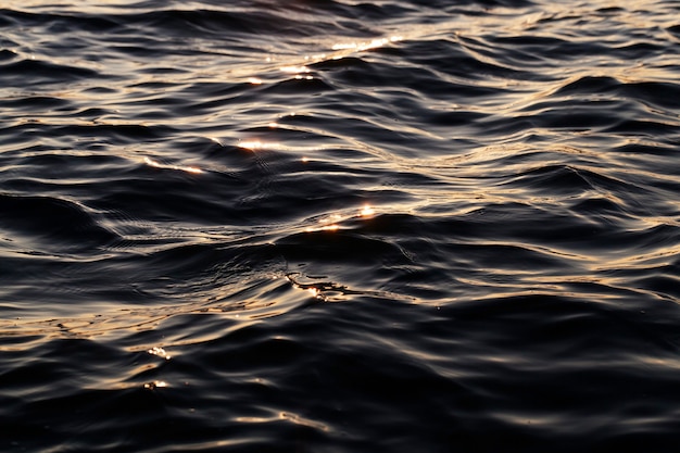 Zwart oppervlak van water met golven van de wind, tijd van de dag in de schemering, close-up, oppervlak onscherp