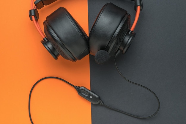 Zwart-oranje hoofdtelefoon met een draad en microfoon op een zwart-oranje achtergrond Een accessoire voor het luisteren naar audio-opnames