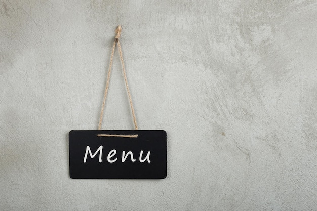 Foto zwart prikbord, schoolbord, schoolbord met tekst menu op grijze cementmuur met kopieerruimte