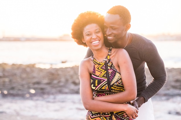 Zwart ras afrikaans afroamerikaans paar in relatie of partnerschap of vriendschap aanraken en genieten van de zonsondergang op het strand in vakantie buiten vrije tijd