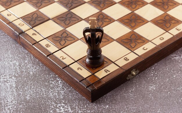Zwart schaakstuk met de hand gesneden in hout op handgemaakt bord. Bedrijfsstrategie, tactiekconcept