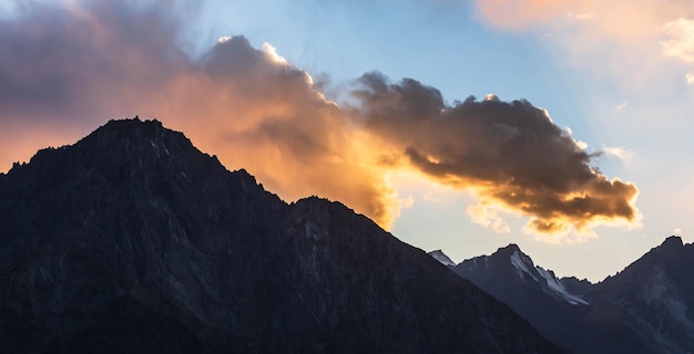 Zwart silhouet van bergketens en oranje wolken op weg naar Shandur Pass bij zonsondergang. Pakistan