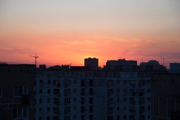 Zwart stedelijk silhouet tegen een oranje zonsondergang