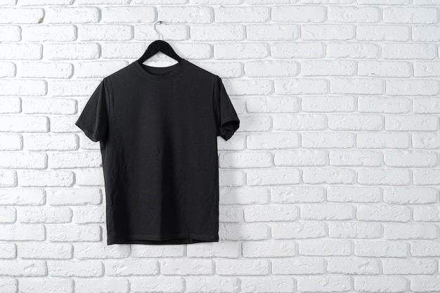 Zwart t-shirt opknoping op een hanger tegen de muur, vooraanzicht