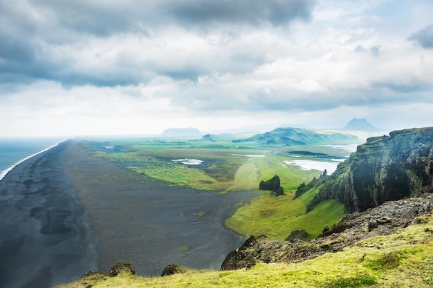 Zwart vulkanisch zand en bergen aan de kust van de Atlantische Oceaan, Zuid-IJsland