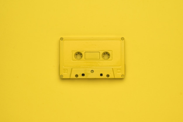 Zwart-wit afbeelding van een gele bandrecorder op een gele achtergrond. Stijlvolle retro-apparatuur om naar muziek te luisteren. Plat leggen.