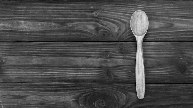 Zwart-wit beeld van een houten lepel op een houten tafel. Gebruiksvoorwerpen gemaakt van hout.