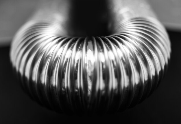 Zwart-wit foto; close-up van roestvrij pijp op zwart-grijze achtergrond.