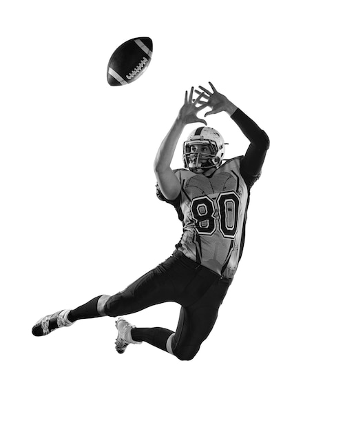 Zwart-wit foto Man professionele american football speler in beweging training vangen bal over witte studio achtergrond Concept van sportcompetitie