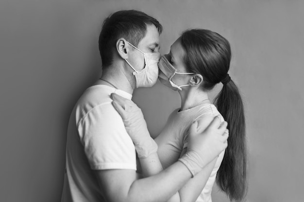 zwart-wit foto van een man en een vrouw die zoenen door beschermende maskers virussen geneeskunde