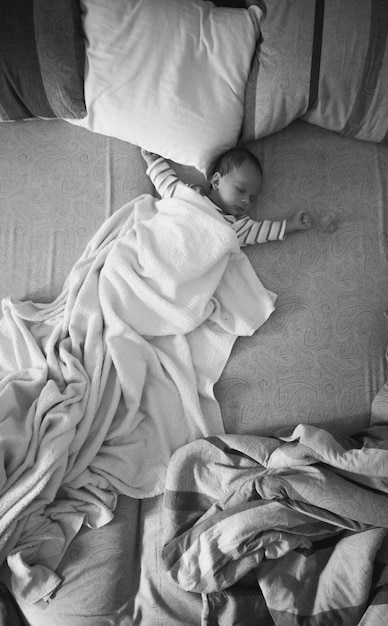 Zwart-wit kleine babyjongen slapen op bed van de ouders