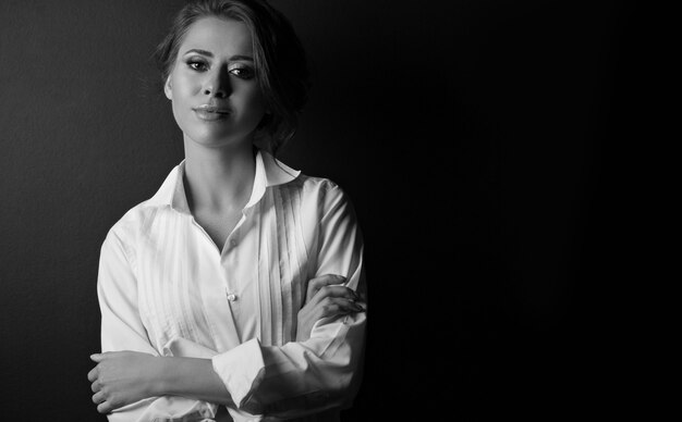 Zwart-wit portret van een elegante jonge vrouw die zich voordeed in de schaduw in de studio. Lege ruimte