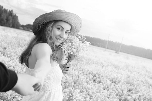 Zwart-wit portret van een jong meisje met een hoed op een enorm veld met bloemen