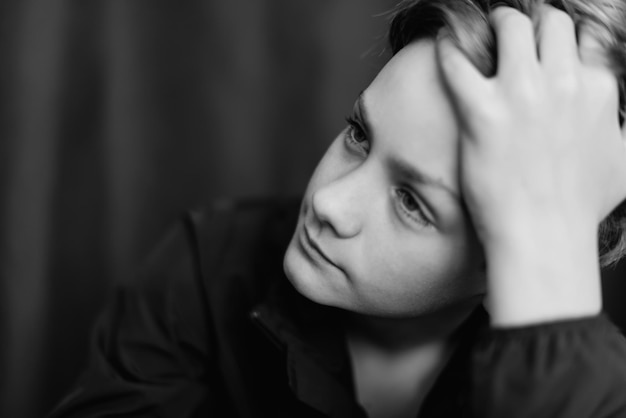 Zwart-wit portret van tienerjongen op donkere achtergrond Low key close-up shot van een jonge tienerjongen Zwart-witfotografie Selectieve aandacht