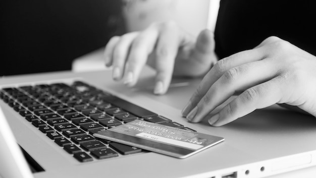 Zwart-wit weergave van creditcard liggend op laptop toetsenbord. Concept van online winkelen en e-commerce.