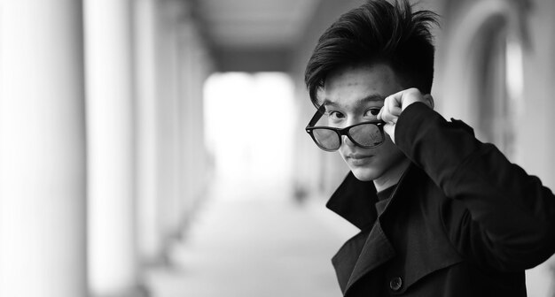 Zwart-witfoto van een Aziatische jongeman die buiten voor de camera poseert