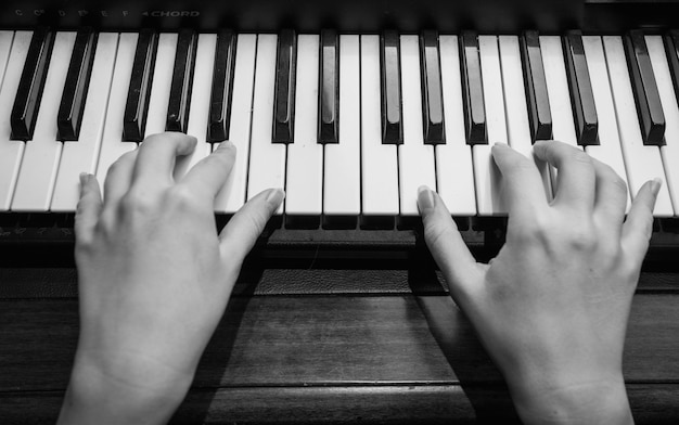 Zwart-witte close-upfoto van vrouwelijke handen die op piano spelen