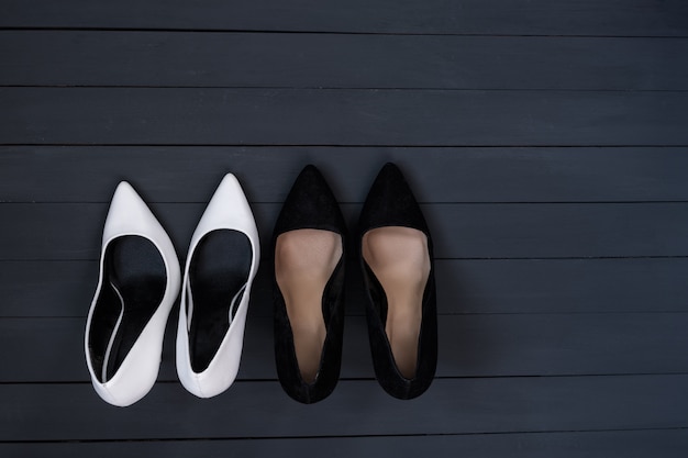 Zwart-witte vrouwelijke schoenen op een zwarte houten achtergrond