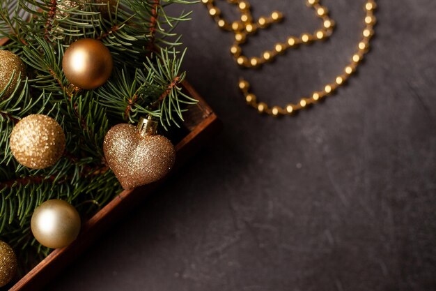 Zwarte achtergrond met houten kist met gouden kerstballen